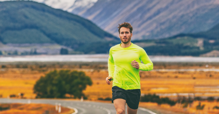 Man in sportswear running on a road with mountains in the background